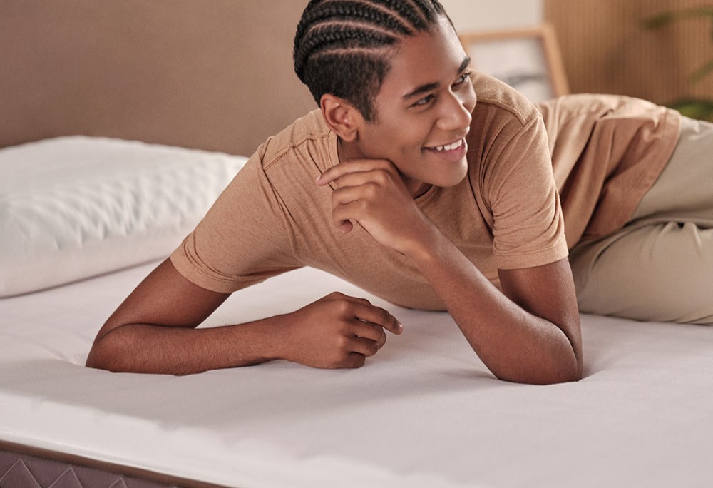 Jovem negro deitado de no pillow top na cama