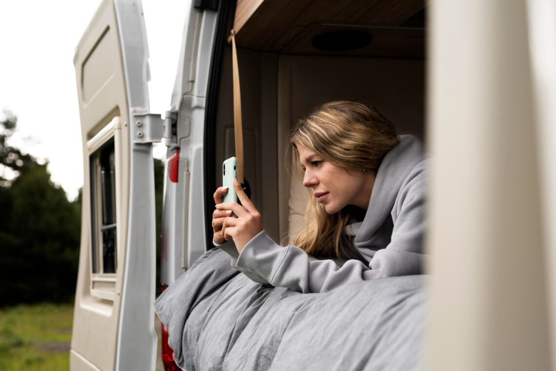Jovem deitada no motorhome mexendo no celular