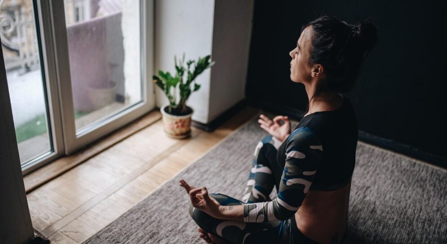 Moça jovem meditando com roupa de academia em casa